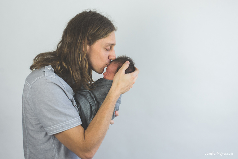 father kissing newborn baby